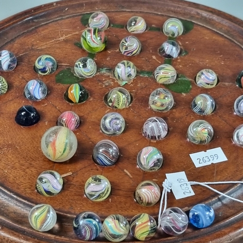 27 - Turned wooden Solitaire board with a collection of mainly Victorian glass marbles.  (B.P. 21% + VAT)