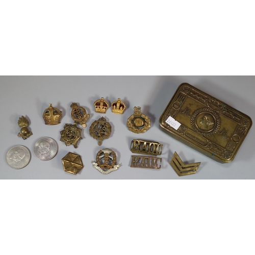 294 - WWI Queen Mary's Brass tobacco box containing an assortment of military cap badges and other insigni... 