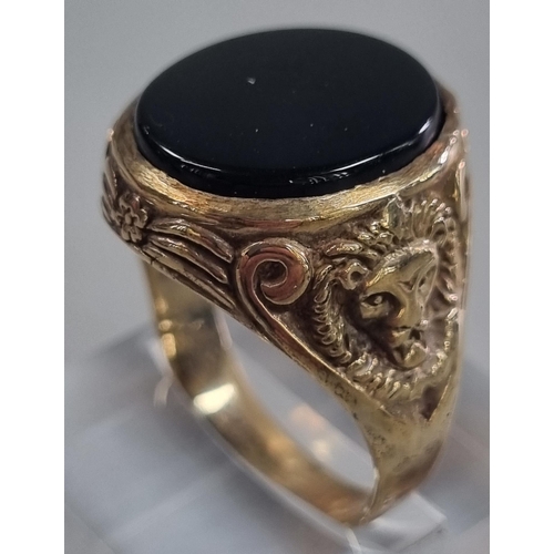 217 - Yellow metal and black hardstone signet ring with lion mask mounts to each shoulder.  7.5g approx.  ... 