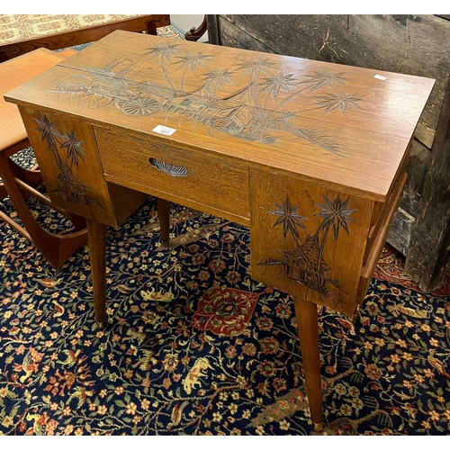 502 - Vintage oak ladies desk/work table, the top carved with figure, horse, carts and palm trees.  67cm l... 