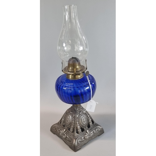 86 - Early 20th century single oil burner, having clear glass chimney above blue glass reservoir on cast ... 