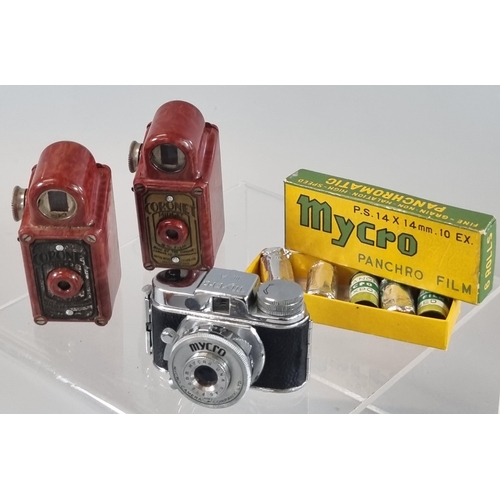 112 - Two Coronet red Bakelite Midget Viewfinder cameras together with a Mycro III A Midget camera in leat... 