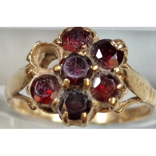 211 - 9ct gold and garnet seven stone flowerhead ring (one stone missing). 2.9g approx. Size O.  (B.P. 21%... 