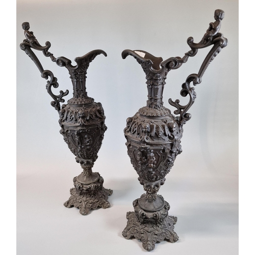 25 - Pair of probably French Gothic cast iron ewers decorated with relief mask heads, cherubs, floral and... 