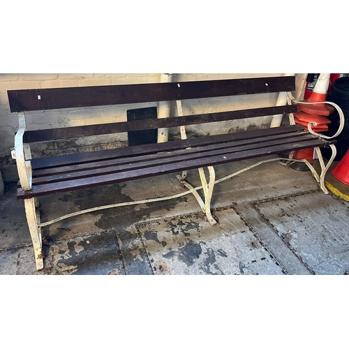 489 - A weathered garden bench with slatted panels and scroll wrought metal supports, 215cm long approx. (... 