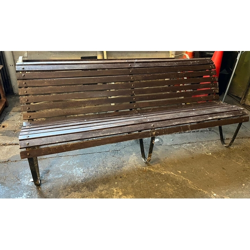 490 - A weathered garden bench with slatted panels and scroll wrought metal supports.  (B.P. 21% + VAT)