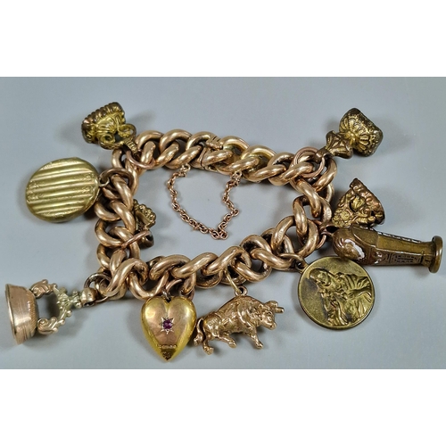 101 - Large chunky 15ct gold charm bracelet comprising: seal fobs, bison, heart with inset red stone, lock...