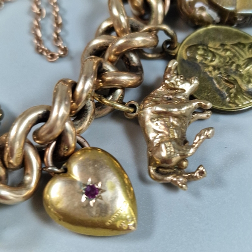 101 - Large chunky 15ct gold charm bracelet comprising: seal fobs, bison, heart with inset red stone, lock... 