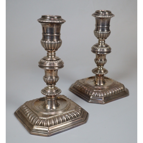 Rare and early pair of Queen Mary 17th century dwarf taper sticks, having overall fluted decoration to the vase shaped stems on square bases with canted angles. London hallmarks for 1699. Engraved armorial devices to three of the four base angles. 13cm high approx. Total weight 17 troy oz approx. (2)  (B.P. 21% + VAT)