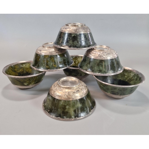 215 - Set of seven Tibetan green hardstone bowls, each with a white metal rim and repoussé white metal abo... 