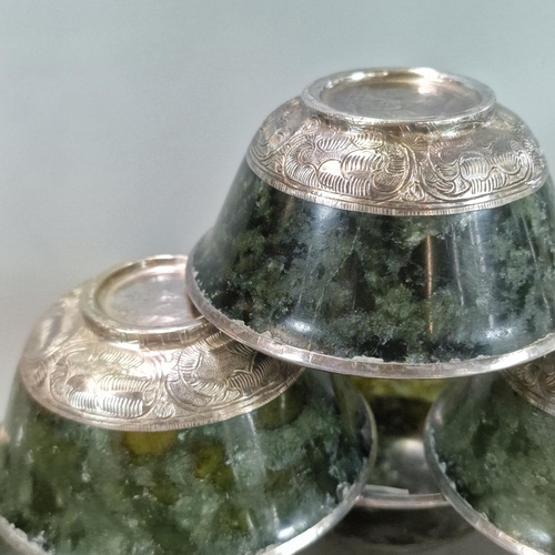 215 - Set of seven Tibetan green hardstone bowls, each with a white metal rim and repoussé white metal abo... 