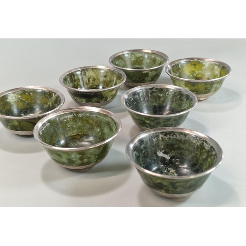 215 - Set of seven Tibetan green hardstone bowls, each with a white metal rim and repoussé white metal abo... 