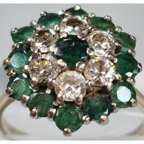 54 - 18ct white gold flowerhead cluster ring inset with thirteen emeralds and six diamonds. 4.8g approx. ... 