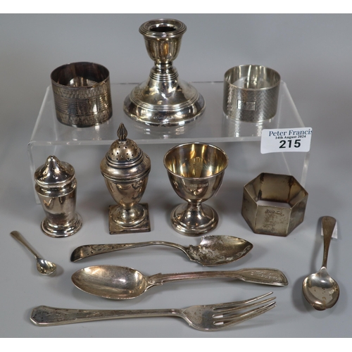 215 - Collection of silver items to include: egg cup, dwarf candle stick, pepperettes, napkin rings, spoon... 