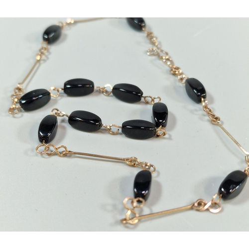 291 - Yellow metal and black polished stone necklace. 8.8g approx. (B.P. 21% + VAT)