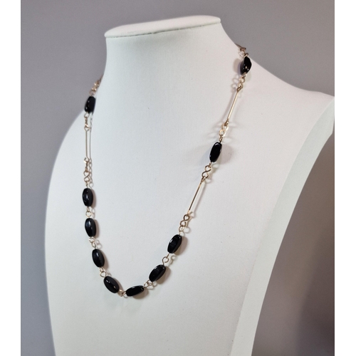 291 - Yellow metal and black polished stone necklace. 8.8g approx. (B.P. 21% + VAT)