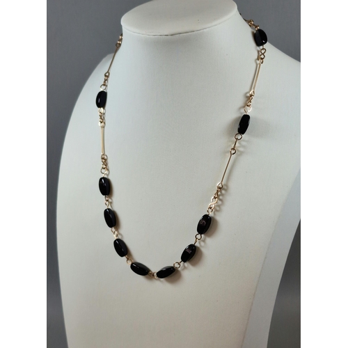 300 - Yellow metal and black polished stone necklace. 8.8g approx. (B.P. 21% + VAT)