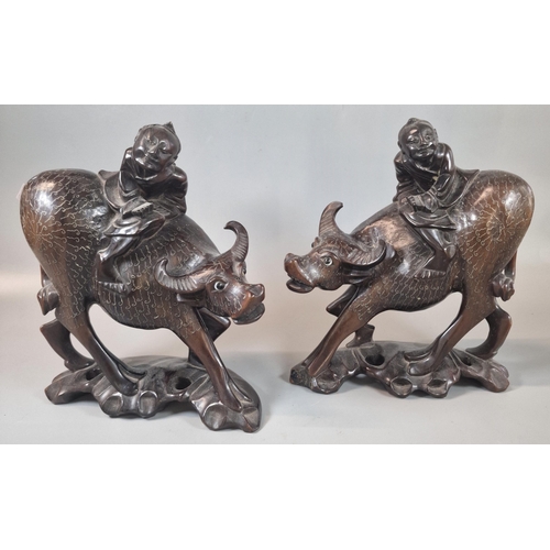 56 - Two Chinese hardwood carvings of boys on buffalo, standing on a naturalistic base. (2) (B.P. 21% + V... 