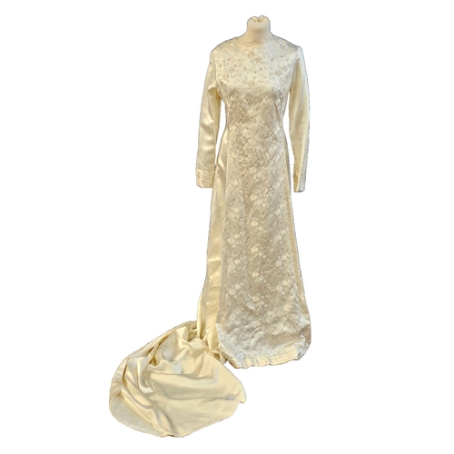 586 - circa 1960s long trained wedding gown of ivory sateen. Cuffs and front panel with self-coloured gilt... 