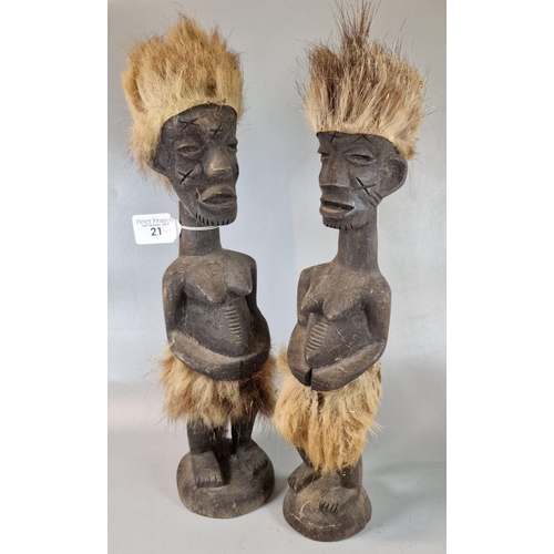 21 - Pair of African carved wooden female figures with natural fur headdresses and skirts. 38cm high appr... 