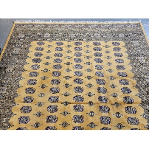 490 - Large mustard ground Bokhara carpet with central repeating geometric panels surrounded by geometric ... 