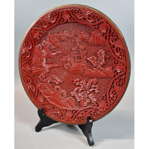 18 - Chinese Cinnabar cabinet plate depicting pagodas, mountains and trees. 25cm diameter approx.  (B.P. ... 