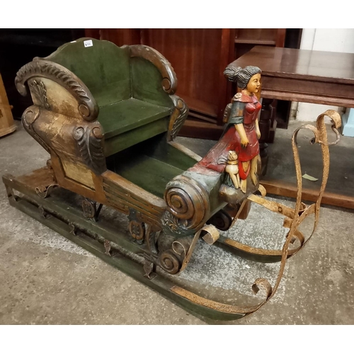 556 - A carved and painted wood child’s sleigh, with a young girl figurehead, flanked by a pair of dogs an... 