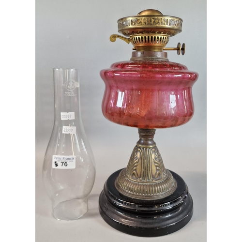 76 - Early 20th century double oil burner lamp having Cranberry glass reservoir on brass relief and eboni... 