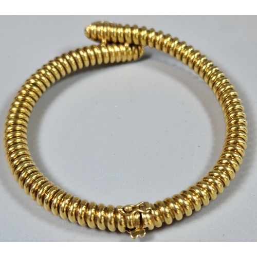 223 - Yellow metal spiral link hollow bracelet, with a crossover section at the front comprising two oval ... 