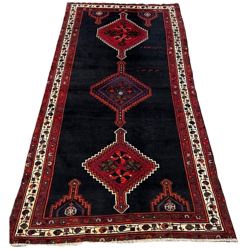 308 - Black ground hand woven Persian Village rug with diamond medallion designs. 250x136cm approx.  (B.P.... 