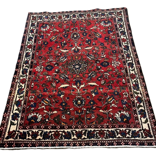 311 - Hand woven red ground Persian Village rug, with floral and foliate designs. 190x145cm approx.  (B.P.... 