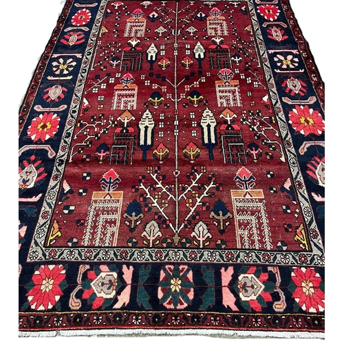 321 - Deep red ground woven Persian Shiraz Village carpet, with repeating flowerhead borders. 355x235cm ap... 