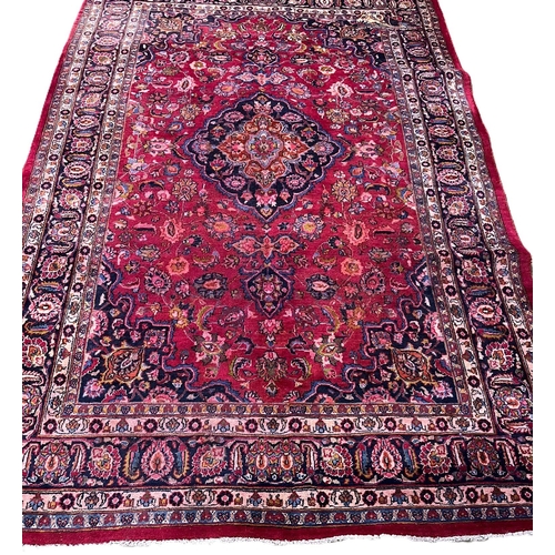 323 - Hand woven red ground Persian Mashad carpet, with traditional floral medallion design. 315x203cm app... 