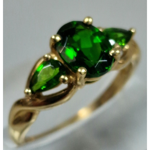 323 - 9ct gold green three stone dress ring. 2.3g approx. Size M1/2.  (B.P. 21% + VAT)