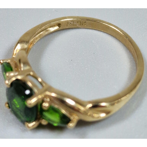 323 - 9ct gold green three stone dress ring. 2.3g approx. Size M1/2.  (B.P. 21% + VAT)