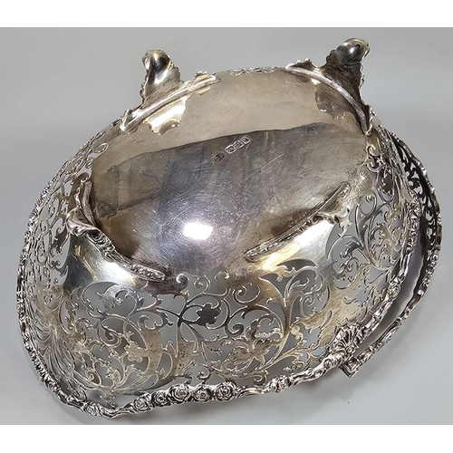 198 - George V silver ornate and pierced basket with swing loop handle on four repoussé scroll feet. By Jo... 