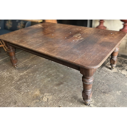 602 - Edwardian oak extending dining table, the moulded top on large baluster turned legs and casters, wit... 