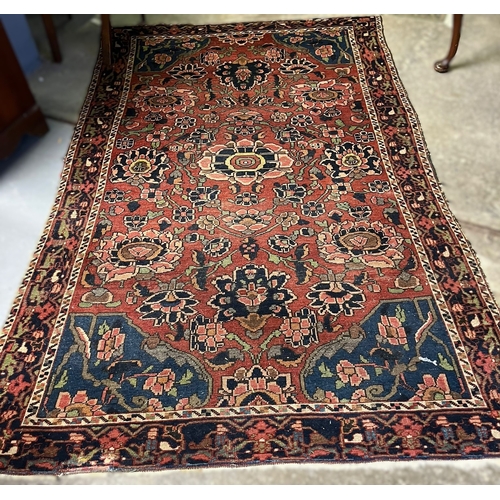 622 - Heriz carpet on a red ground with stylised floral and foliate designs. 215x140cm approx. (B.P. 21% +... 