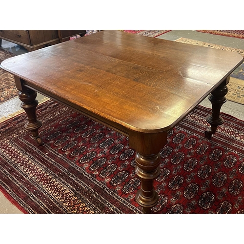 38 - Victorian oak extending dining table, the curved and moulded top above turned baluster legs, brass c... 