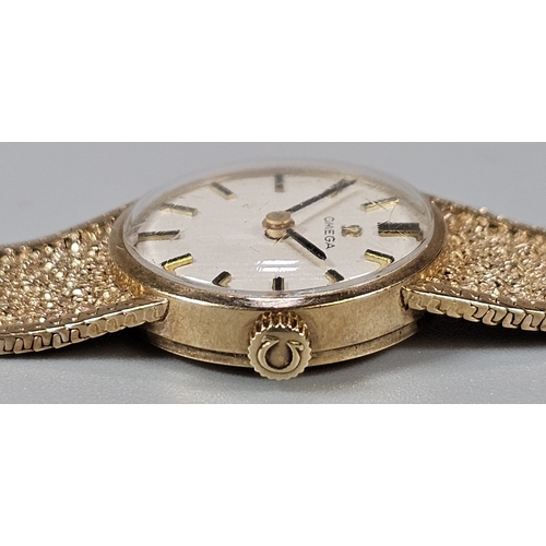 457 - 9ct gold Omega bracelet wristwatch, having circular satin face with Baton numerals on a bark finish ... 