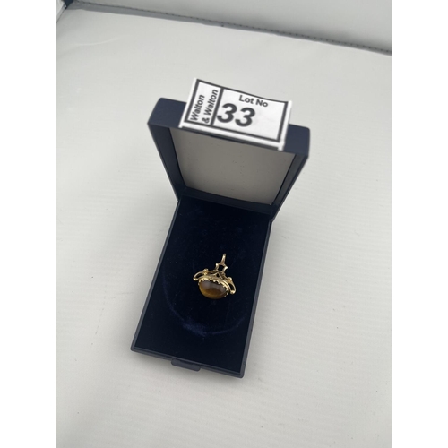 33 - 9ct Gold Albert charm featuring a tiger's eye, 5.5g - Only 10% buyer's premium