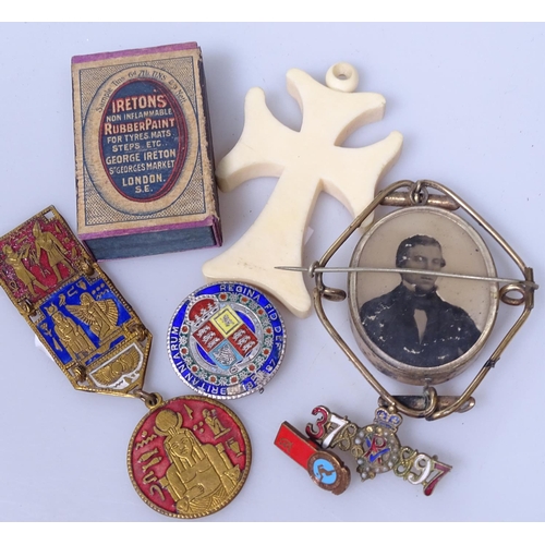 111 - A 19th century memoriam brooch with hair panel, an early matchbox, a cross, and badges