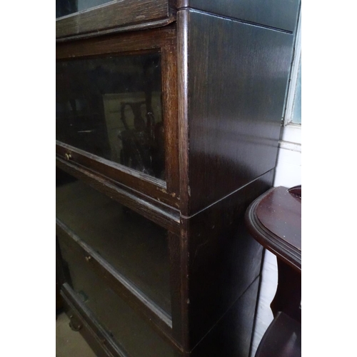 1113 - An oak 4-section globe wernicke style bookcase, with drawer to the base, on carved paw feet, W87cm