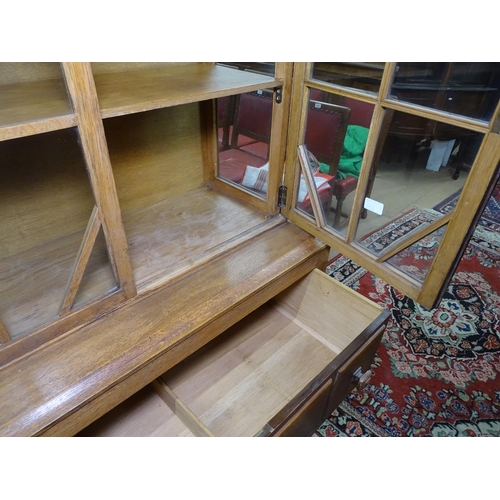 1145 - A Waring & Gillow Arts and Crafts oak glazed cabinet on stand, with maker's plaque to inside of draw... 