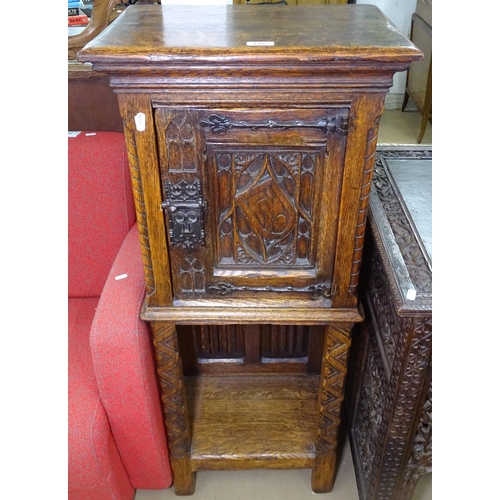 1167 - An Antique oak side cabinet of narrow size, with carved and fielded panels and single door, with she... 