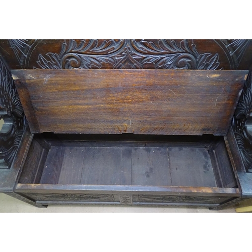 1171 - A 1920s carved and panelled oak monk's bench, W120cm