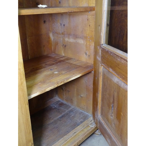 1196 - A Continental pine cabinet with 2 glazed panel doors, on bun feet, W120cm