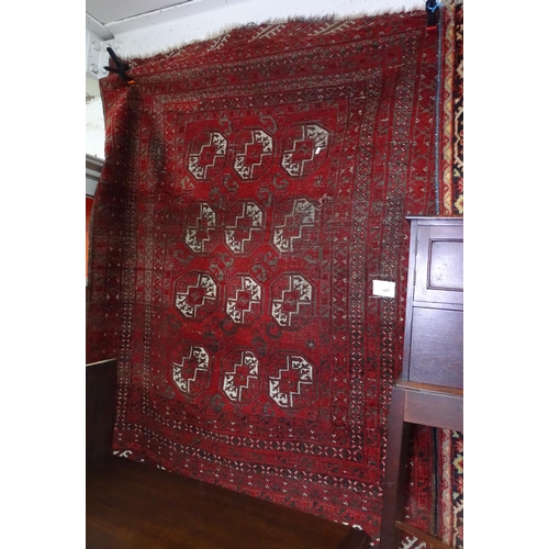 1297 - A red ground Afghan rug with symmetrical pattern and border, 180cm x 150cm approx