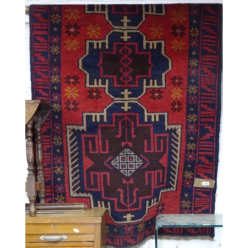 1310 - An Antique red ground Baluchi rug, 202cm x 170cm