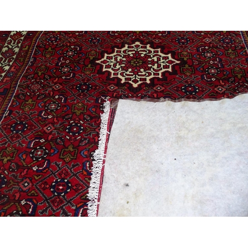 1317 - A red ground wool Persian design rug with symmetrical pattern, 200cm x 140cm